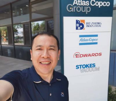 Lawrence Qiu standing by branded sign.