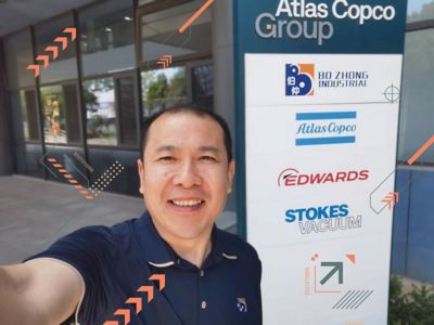 Lawrence Qiu standing by branded sign.