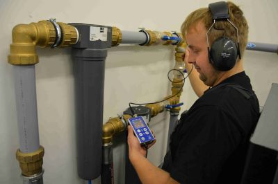 Man measuring luid flow in an industrial piping system