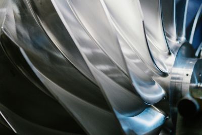 Polished, multi-bladed industrial impeller with curved blades.