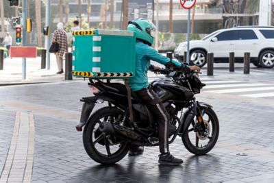 Photo of the delivery men driving a motorcycle. a food deliveryman is standing at a traffic light in green clothes.