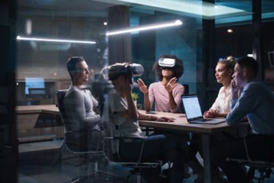 Multiethnic Business team using virtual reality headset in night office meeting  Developers meeting with virtual reality simulator around table in creative office.