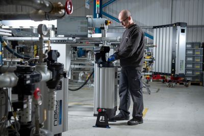 A male nano employee stands over a modular dryer and adjusts the components inside the equipment