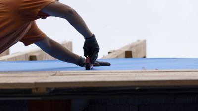 The worker holds the insulation layer with a stapler.