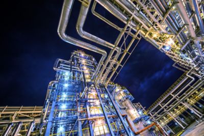 A shot of an oil rig refinery at night, from below looking up to the top with the sky