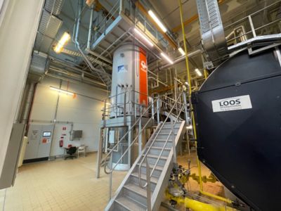 Industrial boiler labeled "PARAT" in a facility with metal walkways and pipes.
