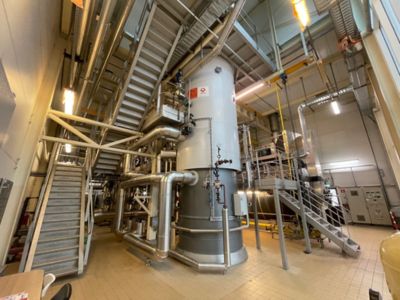 Industrial boiler labeled "PARAT" in a facility with metal walkways and pipes.