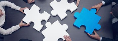 图片显示一群商业人士正在组装拼图以展示团队支持和帮助概念