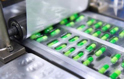 A package of green medication on a production conveyor belt