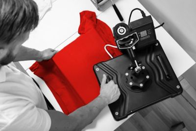 Man printing on t shirt in workshop.