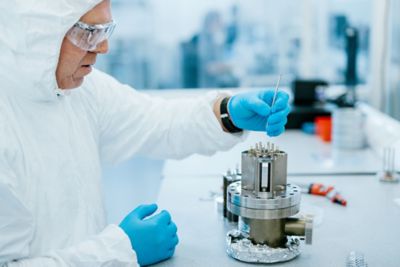 A person in protective gear precisely inserting a component into a machine