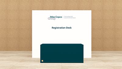 Reception desk branding with Atlas Copco Group logotype on white backdrop and a teal desk in front