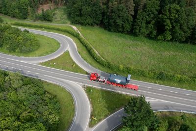 Drohnenbild eines großen Industriekessels, der auf einem Tieflader transportiert wird und für eine sichere Lieferung mit Gurten gesichert ist.