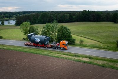 Aerial view of a custom-made industrial boiler mounted on a truck, driving through a lush green landscape.