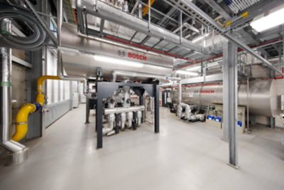 A modern steam plant with several Bosch boilers. he plant is located in a large, industrial building with high ceilings and exposed ductwork.