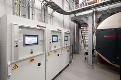 Close-up of multiple boiler controllers. Next to the controllers there's a Bosch boiler visible.