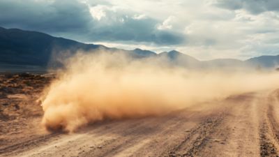 Harsh environments for electronics: Dusty sand cloud kicked up by a speeding vehicle on a rugged road
