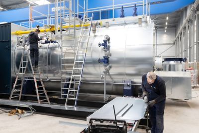 Two service technicians assembling an industrial boiler. 