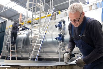 Close-up of a service technician working with tools to assemble an industrial boiler.
