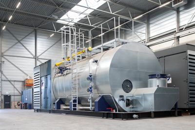 A steam and hot water boiler mounted on a frame in a factory setting of Eco Steam and Heating