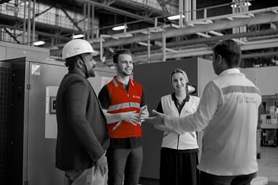 A team having a conversation in front of a machine.