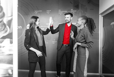 Three smiling colleagues while two of them high five.