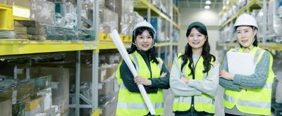 Employees holding documents in a factory store room.