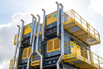 Compresseurs PTS1600 jaunes et noirs triplement empilés avec tuyaux d’échappement et plateformes de maintenance pour projet de rideau de bulles.