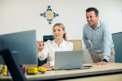 Employee pointing at the screen while colleague looks on with interest