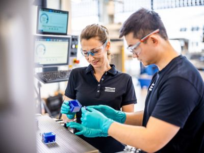 Techniker von Atlas Copco prüfen vakuumvergossene Teile