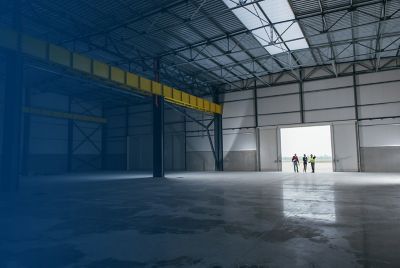 Workers look around an empty warehouse, pointing out different areas as though they are making plans for the space
