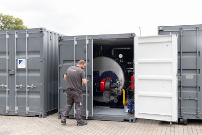 A service technician closing a container with a warm water boiler of Eco Steam and Heating Solutions inside.