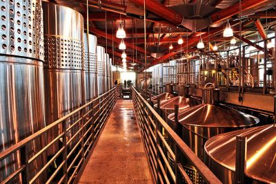 A walkway runs through a warehouse with tanks on either side for winemaking processes