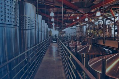 A walkway through a warehouse is lined on either side by winemaking tanks