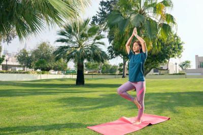Woman holding yoga pose on lawn