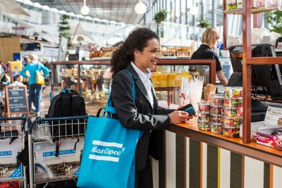 Woman shopping at airport with Atlas Copco branded bag over the shoulder.