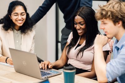 Colleagues collaborating around laptop.